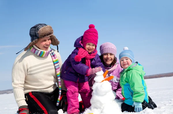 Glückliche Familie macht Schneemann — Stockfoto