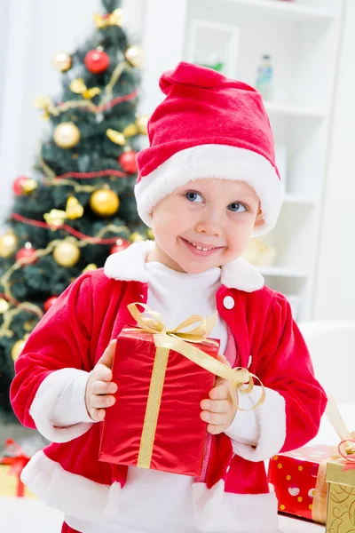 Junge im Weihnachtsmann-Anzug mit Weihnachtsgeschenk — Stockfoto