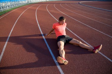 Genç atlet yolda oturur