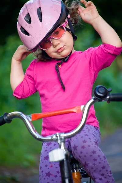 Маленькая девочка в шлеме на велосипеде — стоковое фото