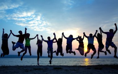 Bir grup insan kumsalda atlama