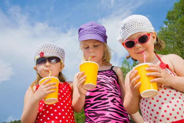 Three little girls drink cocktails — Stock Photo, Image