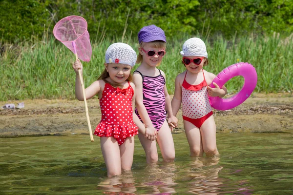 Three little girls go into the water — Stockfoto