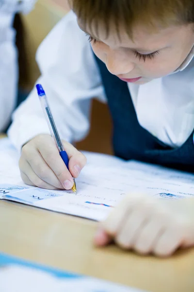 Schooljongen schrijft in notitieblok — Stockfoto