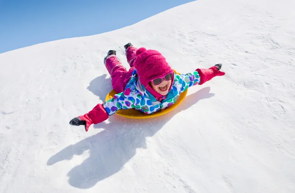 Bambina cavalcando sugli scivoli di neve — Foto Stock