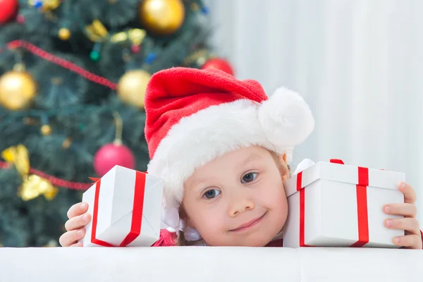 Menina no chapéu de Natal segurando presentes — Fotografia de Stock