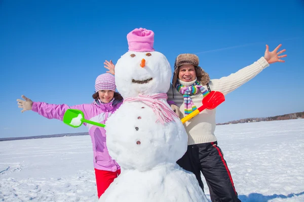 Casal feliz com grande boneco de neve — Fotografia de Stock