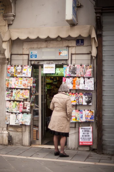 Lady buscando revistas expuestas en el quiosco — Foto de Stock