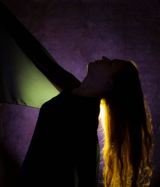 Mavi arka planda poz veren genç ve güzel bir kadının altın ışığına karşı portre.