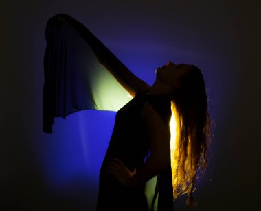 Mavi arka planda poz veren genç ve güzel bir kadının altın ışığına karşı portre.