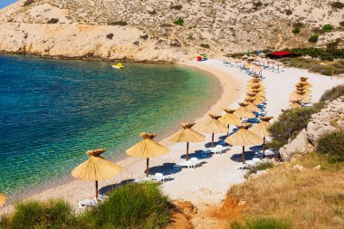 Hırvatistan 'ın Krk adasındaki güzel Oprna plajında saman şemsiyeler