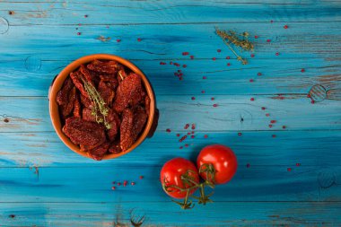 Akdeniz domatesleri bir kâse içinde ve taze domatesler mavi kırsal ahşap üzerinde.