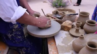 Çömlekçi, kilden bir çömlek kalıbı çıkarmak için bir tekme çarkı kullanır.