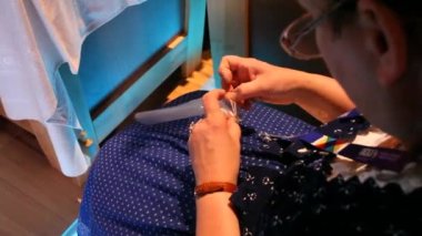 Yaşlı kadın geleneksel şekilde dikiş dikiyor.