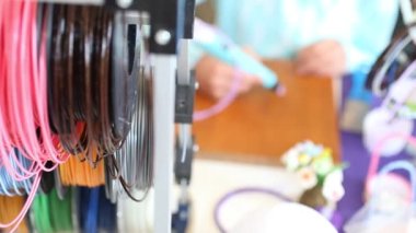 TRIESTE, İtalya - Eylül, 17: 3D çizim. 17 Eylül 2017 'deki Trieste Mini Yapıcı Fuarı sırasında ahşap masanın yanında mavi kalemi tutan çocuğun elleri.