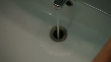 Bornozlu kadın ellerini yıkıyor.