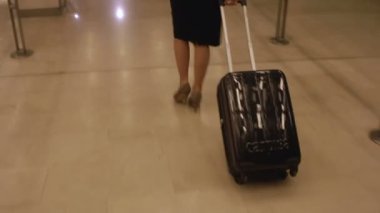 Siyahlar içinde şık bir iş kadını tren istasyonunda bavulu çekiyor.