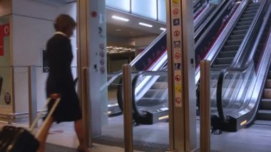 MILAN, İTALYA - 28 Nisan 2013 'te yürüyen merdivende bavulu çeken zarif iş kadını