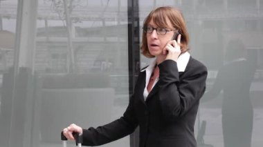 Gözlüklü bir iş kadını şehirdeki akıllı telefondan konuşuyor.