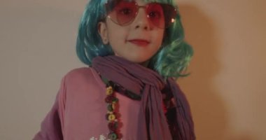 Çocukların fotoğraf çekimi. Disko ışığı arka planında renkli peruk takan çekici bir çocuğun portresi