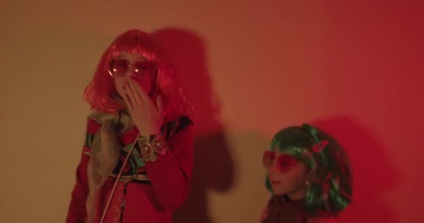 Zwei Kleine Mädchen Mit Bunter Perücke Und Herzförmiger Sonnenbrille Posierten — Stockvideo