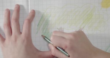 Küçük kızın elleri yeşil bir kalemi olan elma ağacının yeşil yapraklarını boyuyor. 