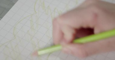 Küçük kızın elleri yeşil bir kalemi olan elma ağacının yeşil yapraklarını boyuyor. 