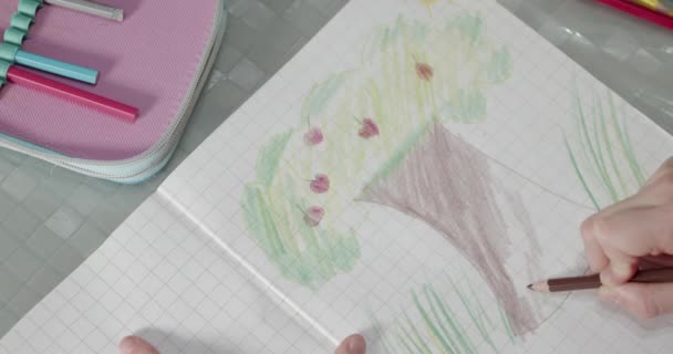 少女の手を閉じて茶色の鉛筆でリンゴの木の絵を着色しています — ストック動画