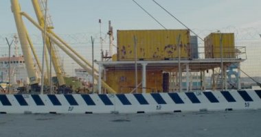 Trieste, İtalya - 31 Ekim: Günbatımında dikenli tellerle kaplı eski iskele duvarları, güneş uzak tel örgülerin arasından batar ve konteynırlar 31 Ekim 2020 'de demir ağın ötesinde istiflenir.