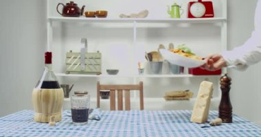 Garson masaya domates soslu bir tabak spagetti koyar. Masa örtüsü, bir şişe şarap ve parmesan masaya serildi.. 