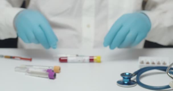分析实验室的医生手在摄像机前展示了一位病人包扎的血检结果 测试结果写在试管里 医生穿着一件白色的外套和蓝色的手套 — 图库视频影像