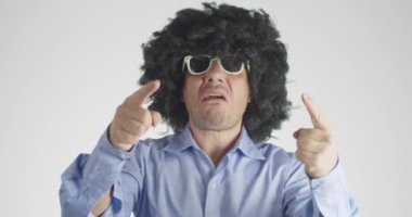 Kıvırcık saçlı bipolar bir adamın duygularını iyiden kötüye değiştirmesinin ön görüntüsü öfkeyle bağırmaya başladı ve hemen sonra gri arka planda izole edilmiş pelüş filini kucaklayıp kucaklamaya başladı..