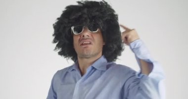 Kıvırcık saçlı bipolar bir adamın duygularını iyiden kötüye değiştirmesinin ön görüntüsü öfkeyle bağırmaya başladı ve oyuncak ayısını kucaklayıp kucakladıktan hemen sonra gri arka planda soyutlandı..