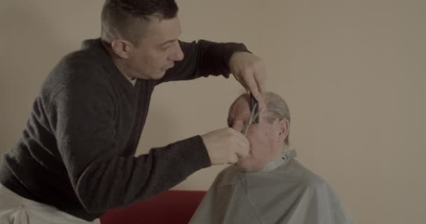 Мужчина Стрижет Волосы Седого Мужика Ножницами Расчёской — стоковое видео