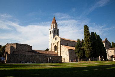Aquileia 'daki Santa Maria Assunta Bazilikası' nın panoramik manzarası. Via Sacra 'da yer alır, Piazza del Capitolo' ya bakar, çan kulesi ve vaftiz töreniyle birlikte. İtalya 