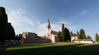 Aquileia 'daki Santa Maria Assunta Bazilikası' nın panoramik manzarası. Via Sacra 'da yer alır, Piazza del Capitolo' ya bakar, çan kulesi ve vaftiz töreniyle birlikte. İtalya 