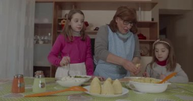 Torunları genç büyükannesine Arancini pişirmesinde yardım ediyor, tipik Sicilya yemekleri.