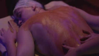 Rahatlamış genç bir kadın kaplıcada çamurdan cilt tedavisi görüyor. Güzellik merkezinde güzellik uzmanı tarafından kilden maske taktıran güzel bir genç kadının portresi..