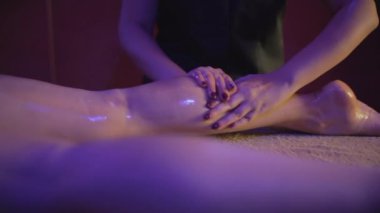 Genç bayan, ahşap kaplıca yatağına uzanmış yağ ile masaj yaptırıyor.