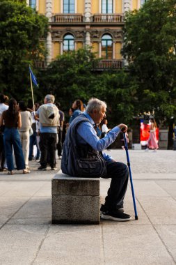 Milan, İtalya - 24 Mayıs 2025: Yürüyen bastonlu yaşlı adam şehir meydanında yürüdükten sonra dinleniyor