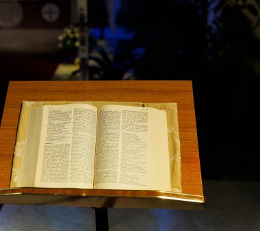 Kilise kürsüsüne yerleştirilmiş, eski bir ahşap kilise mabedinin içine işlenmiş İncil. Yumuşak ışık, ruhsal atmosfer, İyi Çoban Kilisesi 'ndeki basit Hıristiyan ayarı, Trieste..