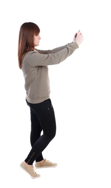 Πίσω όψη του στέκεται νεαρή όμορφη γυναίκα χρησιμοποιώντας ένα κινητά pho — Φωτογραφία Αρχείου