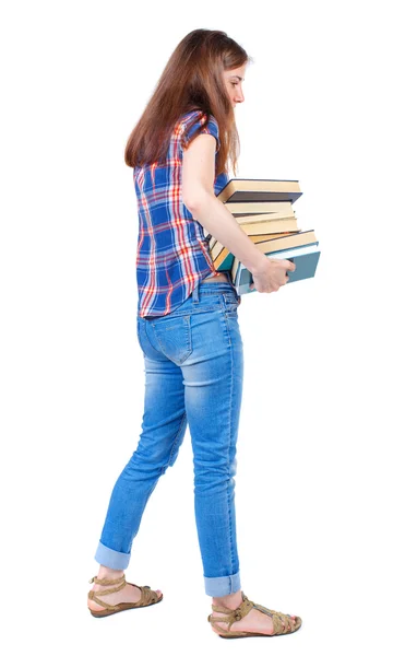 Mädchen trägt einen schweren Stapel Bücher. Ansicht von hinten. — Stockfoto