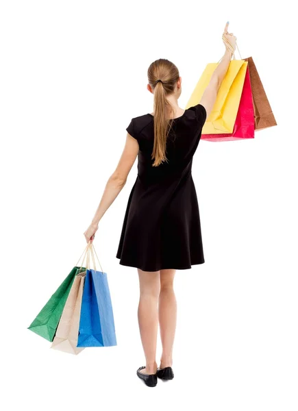 Back view of woman  with shopping bags pointing . — Stockfoto