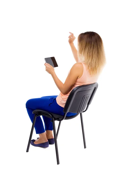 Back view of pointing woman sitting on chair and looks at the sc — Fotografia de Stock