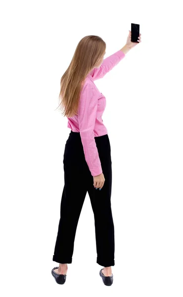 Vista posterior de hermosa mujer joven de pie y usando un móvil —  Fotos de Stock