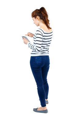 arkadan görünüşü mobil bir fon kullanan duran genç güzel kadın