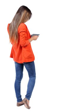 arkadan görünüşü mobil bir fon kullanan duran genç güzel kadın