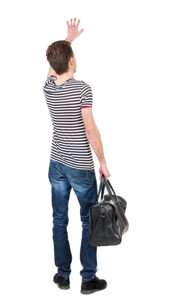 Widok człowieka z powrotem z torbą macha w pozdrowienie. — Zdjęcie stockowe