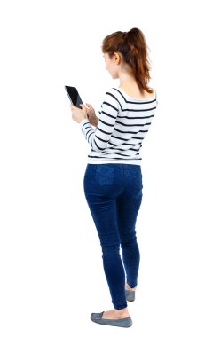 arkadan görünüşü mobil bir fon kullanan duran genç güzel kadın